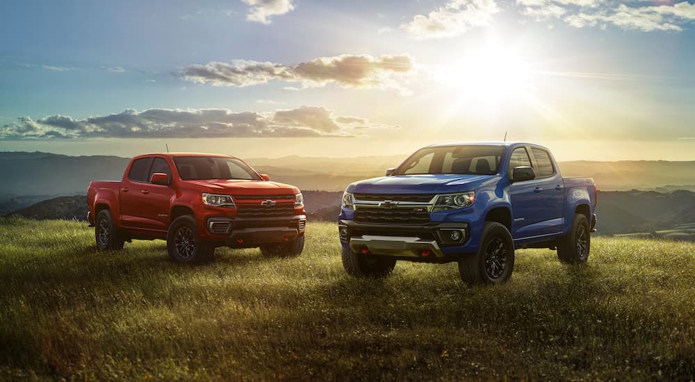 A red and a blue 2022 Chevy Colorado are shown parked in a field after leaving a used Chevy dealer.