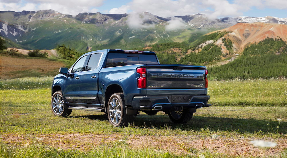 A blue 2025 Chevy Silverado 1500 High Country is shown from the rear at an angle.