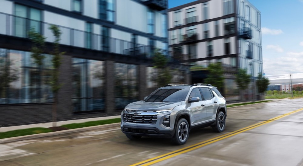 A silver 2025 Chevy Equinox for sale driving on a city street.