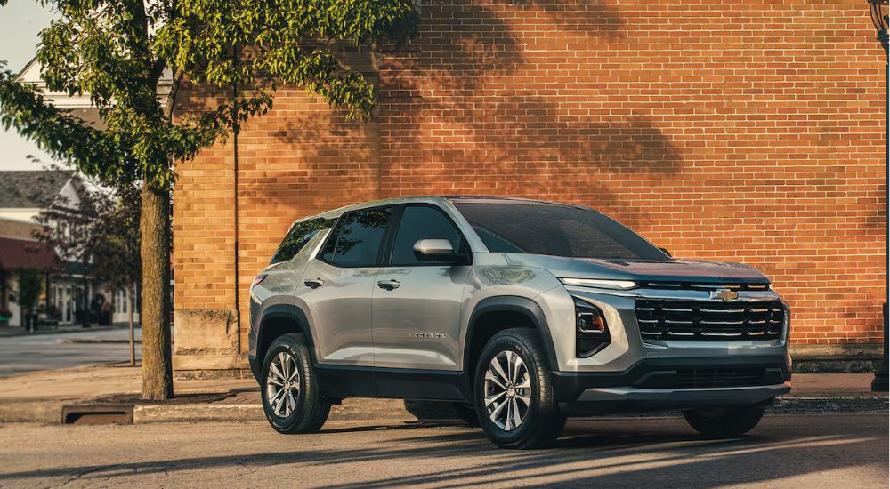 A silver 2025 Chevy Equinox LT parked in front of a brick wall.