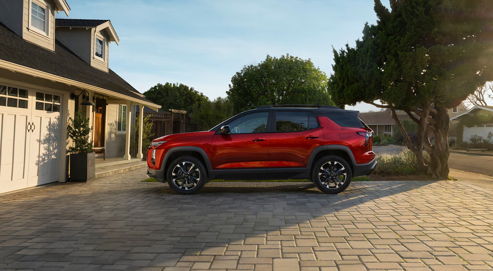Side view of a red 2025 Chevy Equinox RS parked in a driveway.