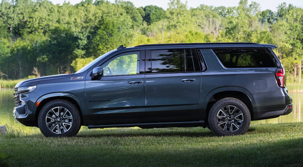 A blue used 2021 Chevy Suburban Z71 parked near a pond