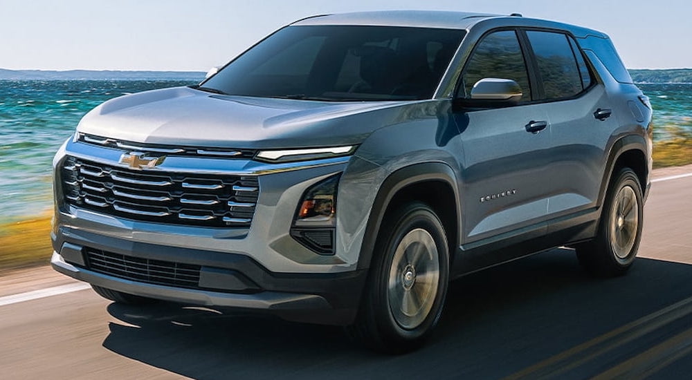 Silver 2026 Chevy Equinox  driving down a road.