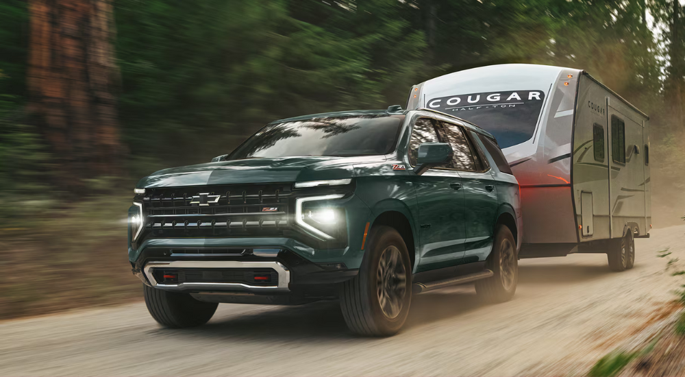 A green 2026 Chevy Tahoe Z71 towing a trailer.