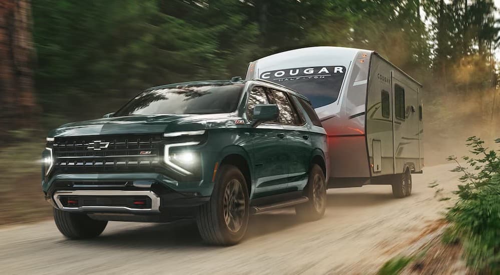 A green 2026 Chevy Tahoe Z71 towing a trailer.