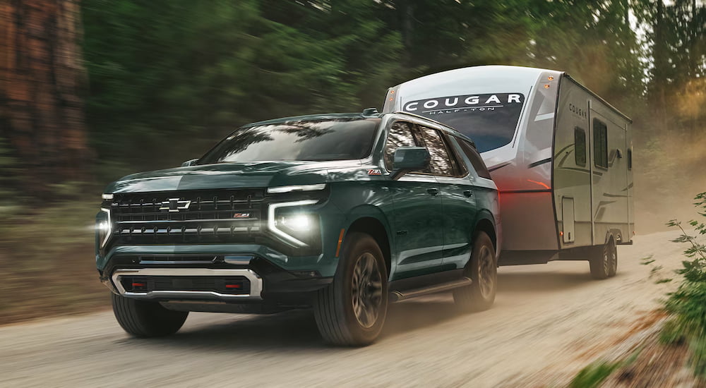 Green 2026 Chevy Tahoe towing a camper.