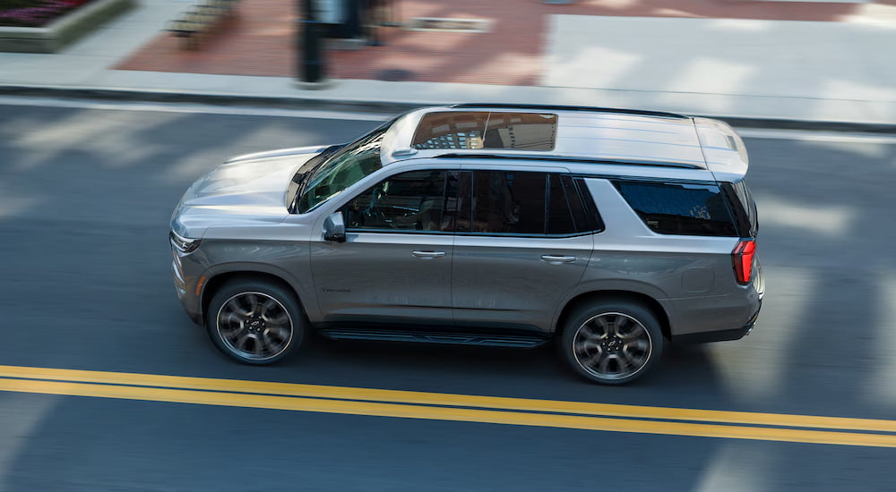 High view of a silver 2026 Chevy Tahoe driving down a city street.