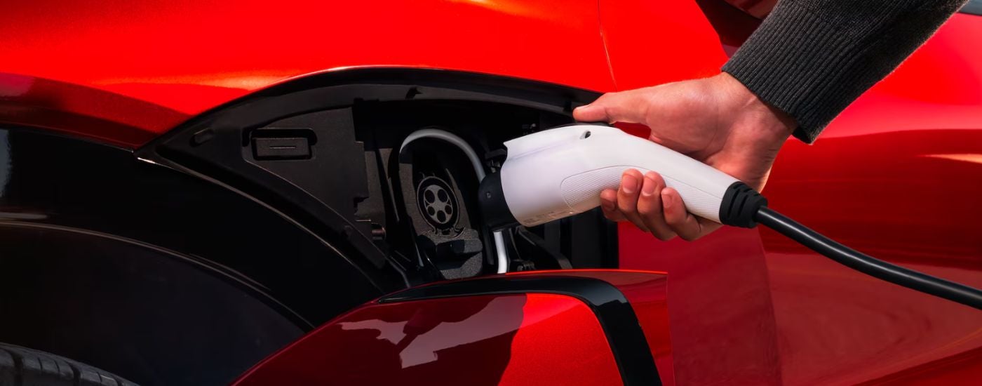 A red 2026 Chevy Blazer EV being plugged into a charger.