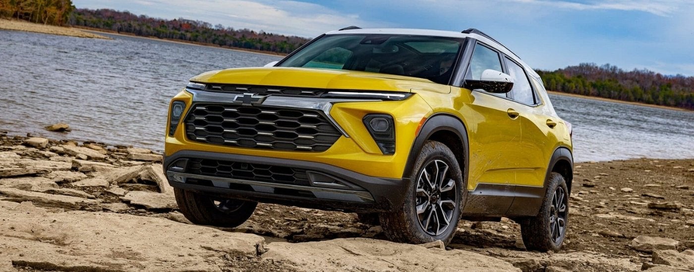 A yellow 2025 Chevy Trailblazer shown parked on a rocky beach.