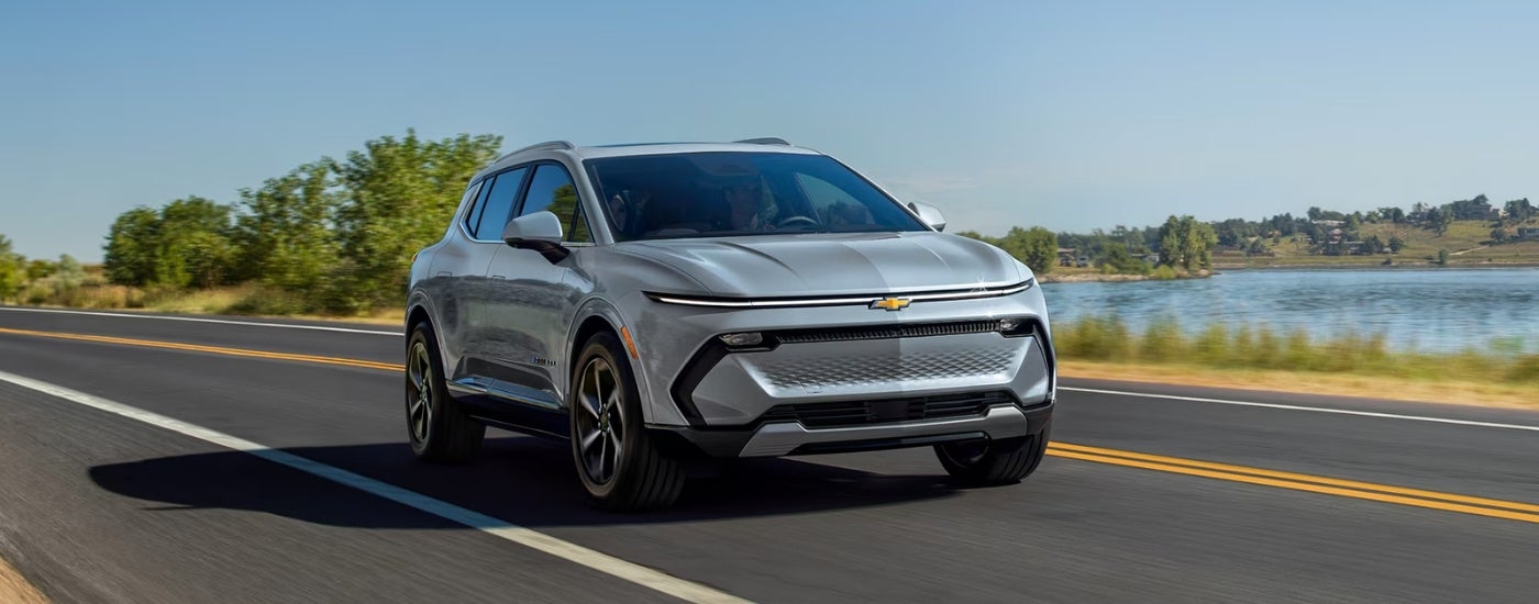 A grey 2025 Chevy Equinox EV is shown driving to a Chevy dealer.