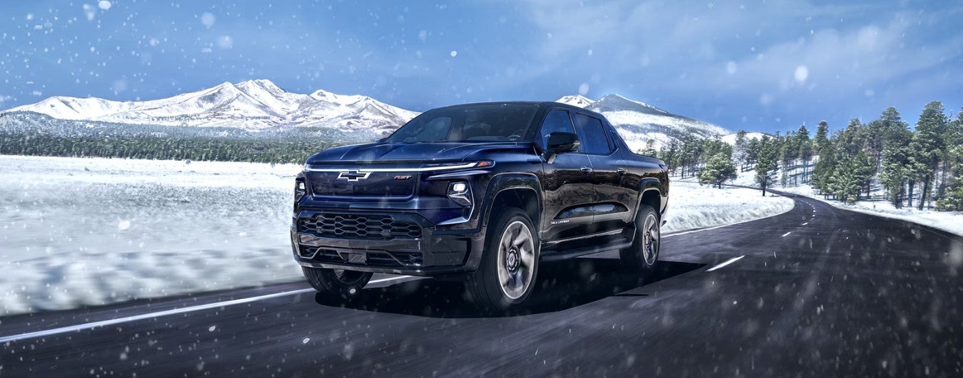 A black 2024 Chevy Silverado EV RST driving to a Chevy dealer near Burnsville.