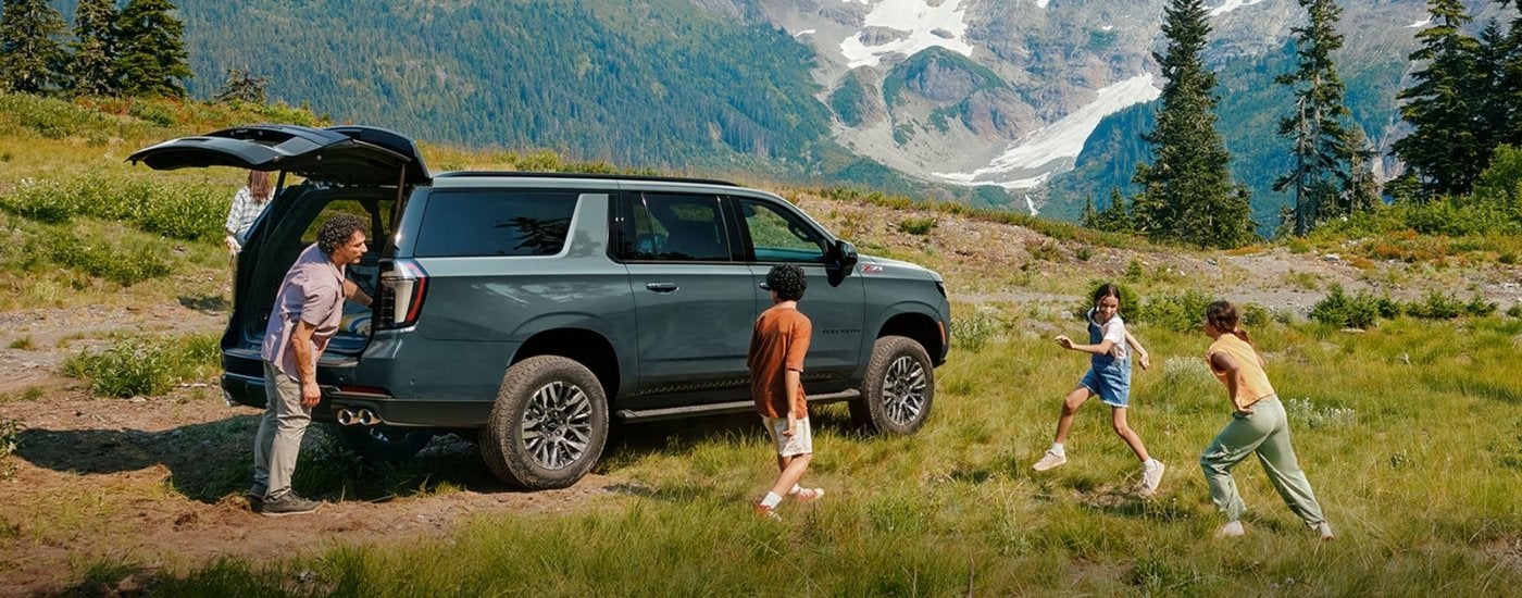 A family near a green 2025 Chevy Suburban Z71.
