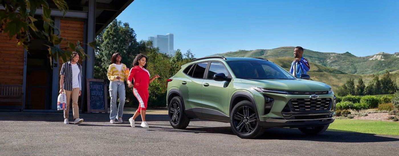 A green 2026 Chevy Trax ACTIV parked near several people.